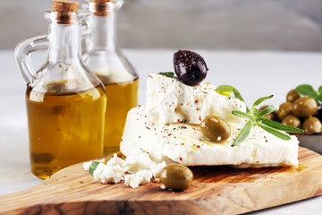 Greek cheese feta with herbs and olives on rustic table.