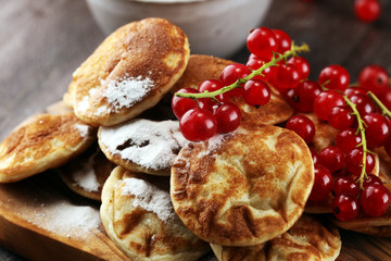 Pancakes or puffertjes with berries and maple syrup on rustic table