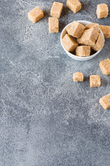 Brown cane sugar cubes on concrete background. Copy space