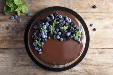 Fresh delicious homemade chocolate cake with berries on wooden table, top view