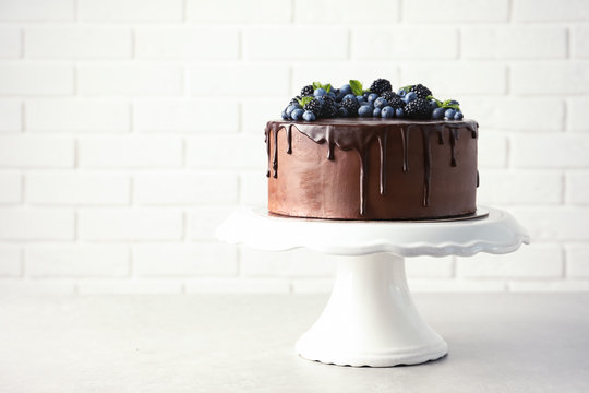 Fresh delicious homemade chocolate cake with berries on table against brick wall. Space for text