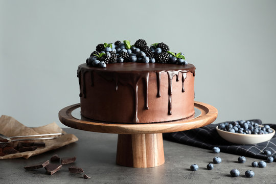 Fresh delicious homemade chocolate cake with berries on table against gray background
