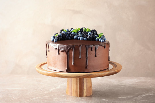 Fresh delicious homemade chocolate cake with berries on table against color background