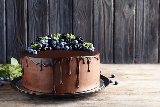 Fresh delicious homemade chocolate cake with berries on table against wooden background. Space for text