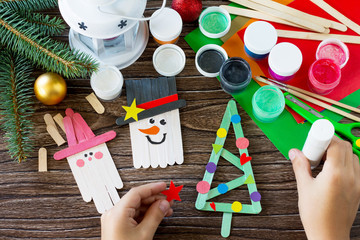 The child glues the parts Christmas decoration or Christmas gift - Snowman, fir-tree and Santa....