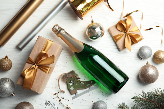 Christmas composition with bottle of champagne and gifts on wooden background, top view