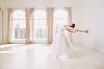 Ballerina dancing in a studio on white background window.