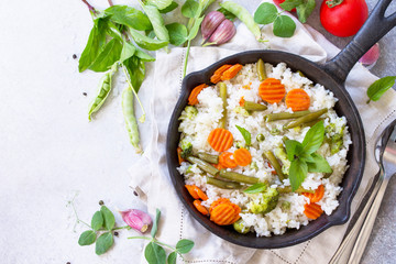 Healthy food: Fried rice with vegetables. Prepared and served in a cast-iron frying pan. Diet menu. Top view flat lay background. Copy space.
