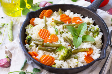 Healthy food: Fried rice with vegetables, close-up. Prepared and served in a cast-iron frying pan. Diet menu.