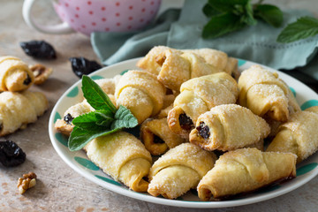 Homemade cookies with dried prunes and walnuts on a plate on a table, bagels.