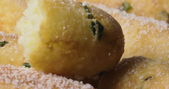 Crocchette di patate infarinate con prezzemolo disposte su un piatto bianco rotante con basilico e formaggio grattugiato. Dieta vegetariana e vegana. Vista macro.