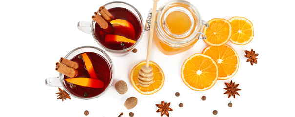 Hot red mulled wine, bee honey, slices of oranges and spices isolated on white background. Wide photo.