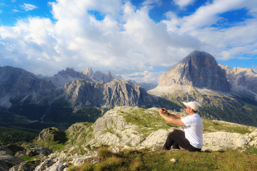 Naklejka na ściany i meble Man takes pictures with his cell phone to the mountain landscape of the Alpine peaks.