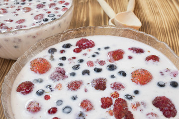 berries in milk on wooden background, healthy food concept