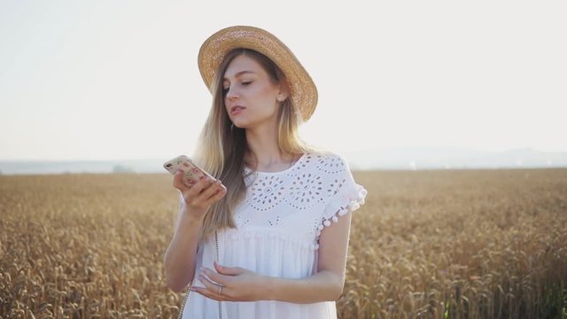 Portrait beautiful woman with hat speak on phone smile girl fashion model in slow motion on field wheat on sunset smartphone countryside female freedom happiness nature outdoor summer slow motion