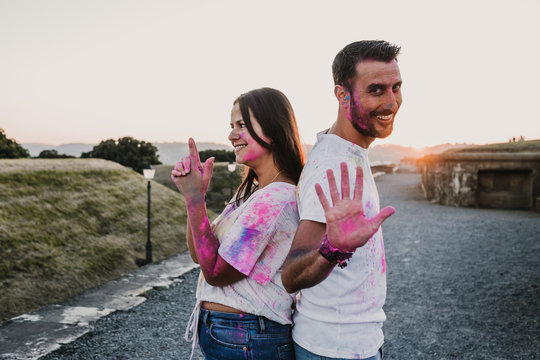 .Young and beautiful couple in love enjoying an afternoon outdoors in Gijón, northern Spain. A funny couple throwing holi powder and staining many colors. Lifestyle..