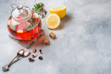 Glass teapot with tea, mint and lemon on grey table with copy space