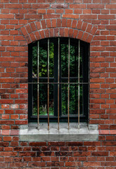 Vergittertes Rundbogenfenster eines Backsteinhauses
