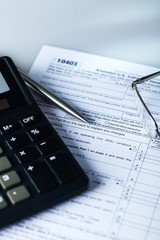 Calculator, Glasses and Pen Lying on the 1040 Tax Form on the