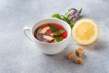 Cup of tea, mint and lemon on grey table with copy space