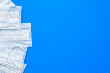 Flu prevention. Medical face masks on blue background top view copy space
