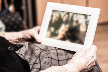 Elderly woman holding a picture frame and watching picture