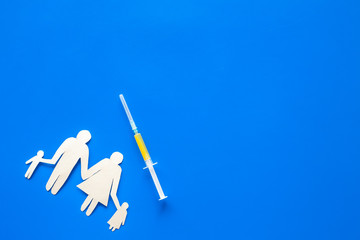 Vaccination for healthy family, vacctination of children. Flu. Syringe near family cutout on blue background top view copy space