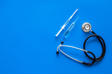 Infuenza, flu vaccine in syringe near stethoscope on blue background top view copy space