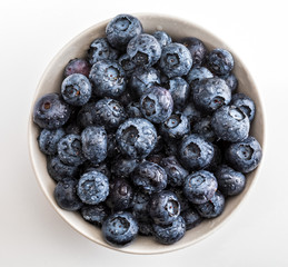 Fresh and raw blueberries in delicate white porcelain bowl. Isolated and on white background.