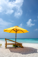 A sun lounger and a beach umbrella on a deserted beach; perfect vacation concept; blue sky; amazing sea