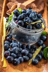 Fresh blueberries, sugar, lemon, mint. ingredients to make jam at home. On wooden background.
