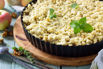 Apples crumble, crisp in baking dish on wooden table.