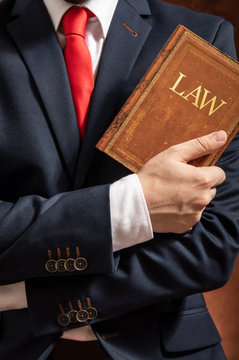 Lawyer stands with crossed hands with law book.