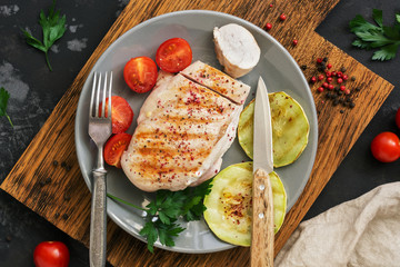 Chicken breast barbecue with vegetables on a dark concrete background. Top view, overhead, flat lay.