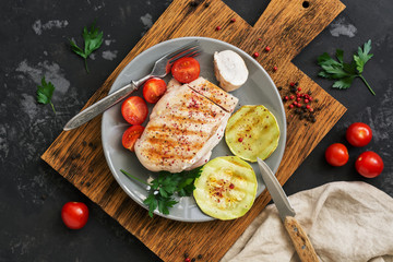 Grilled chicken fillet with vegetables served on a gray plate. Top view, overhead, flat lay.
