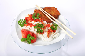 Ryż na białym talerzu z kotletem schabowym, sosem, pomidorem, zieloną petruszką i bazylią. - obrazy, fototapety, plakaty
