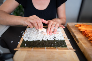 Woman making at home Japanese sushi rolls