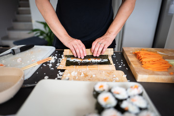 Woman making at home Japanese sushi rolls
