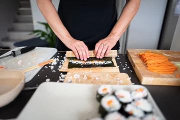 Poster de jardin Bar à sushi Woman making at home Japanese sushi rolls