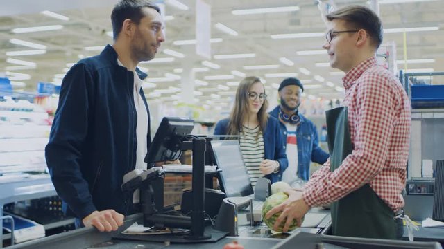 At the Supermarket: Checkout Counter Happy Customer Chats with Friendly Cashier who Scans Fresh Groceries and Fruits. Modern  Shopping Mall with Wireless Paying Terminal System.