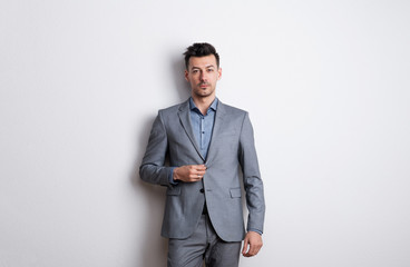 Portrait of a young man in a studio, dressed in gray suit.