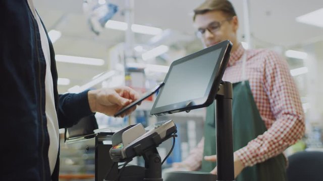 At the Supermarket: Checkout Counter Customer Pays with Smartphone for His  Food Items. Big Shopping Mall with Friendly Cashier, Small Lines and Modern Wireless Paying Terminal System.