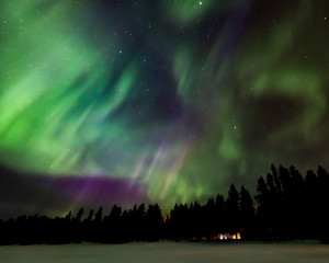 Aurora over cabin in the forest