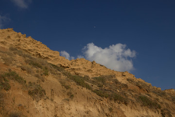 sandy cliffs against the background of a blue picturesque sky with clouds