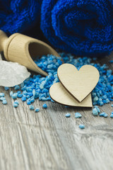 Wooden heart put on the wooden table with a blue towel. Spa concept.