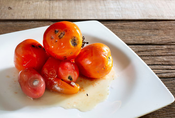 Rotten tomatoes with fungus and Drosophila on old wooden background