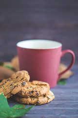 A cup of coffee and biscuits on a wooden background. Autumn foliage