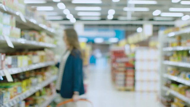 Blurred Footage at the Big and Bright Supermarket. People and Customers Walking through the Aisles Buying Different Useful Items.
