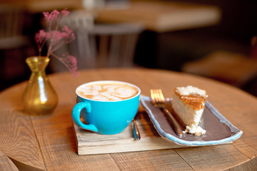 Blue coffee cup baked fruit pie on wooden tray over modern cafe iterior.