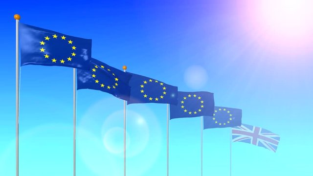 The flag of the UK member of the European Union is developing in the wind in the sun with a glare from the lens on a blue background.